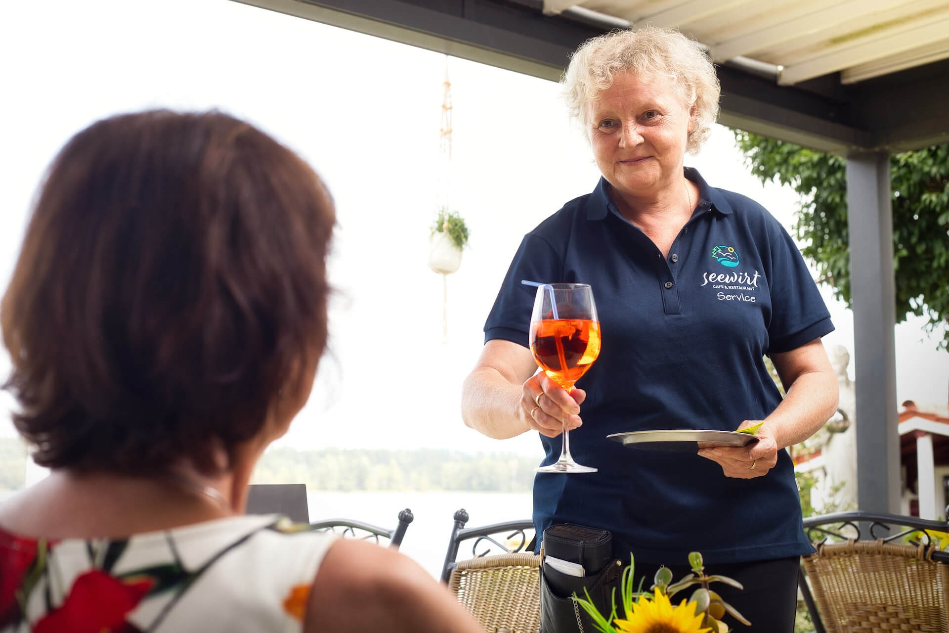 Seewirt Neubäu - Service bringt Gast einen Aperol Spritz