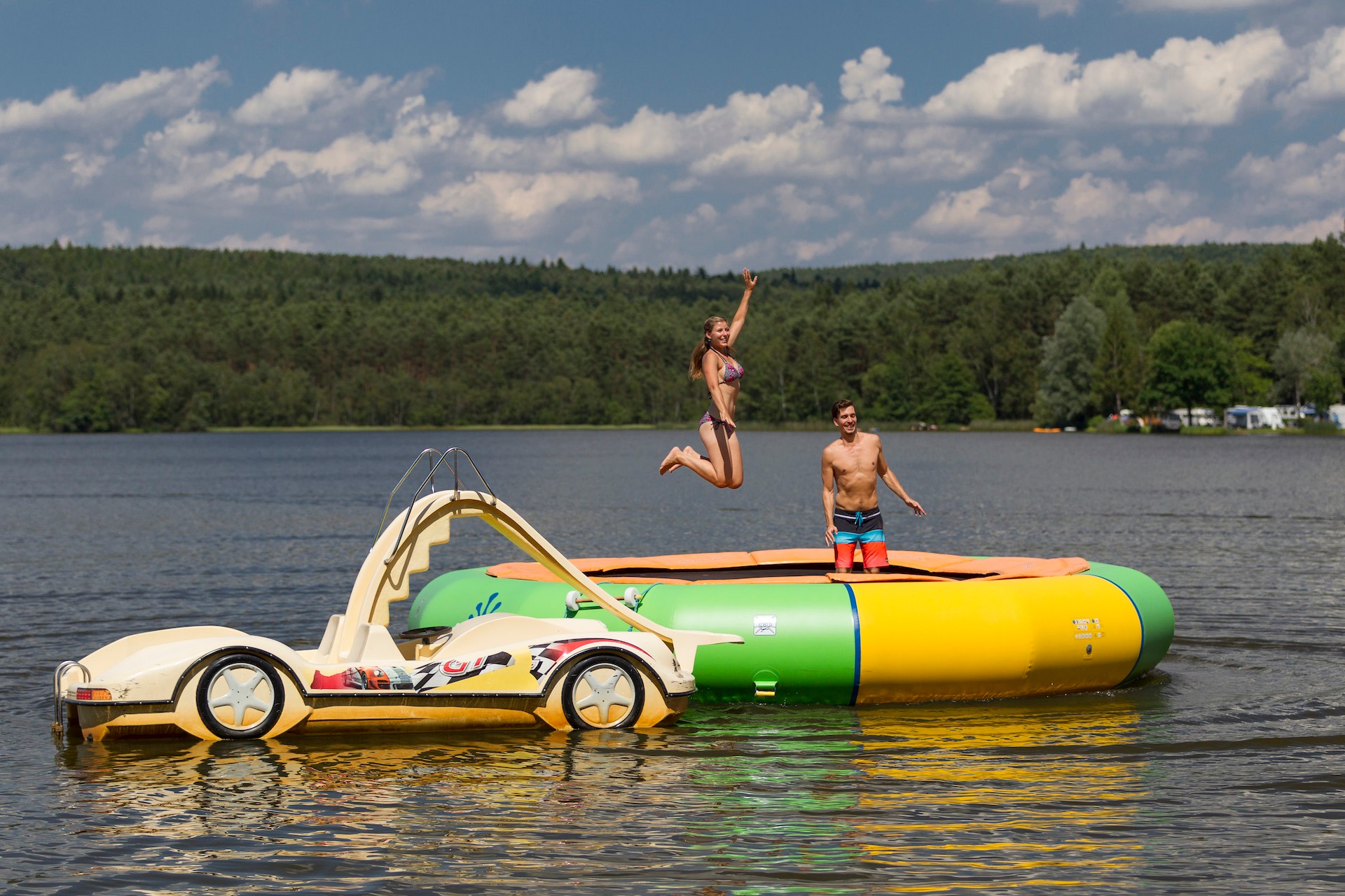 Pärchen am Wassertrampolin mit Tretboot davor